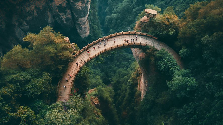 Puente de piedra en arco entre dos acantilados cubiertos de bosque